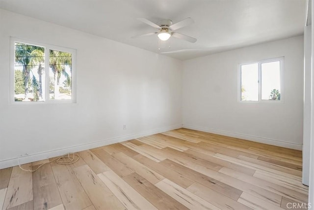 empty room featuring a ceiling fan, wood-type flooring, a healthy amount of sunlight, and baseboards