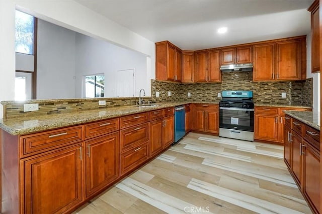 kitchen featuring dishwashing machine, stainless steel gas range oven, under cabinet range hood, a sink, and backsplash