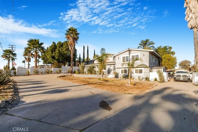 view of front of house featuring a residential view, concrete driveway, fence, and stucco siding