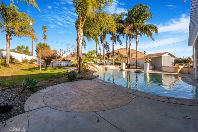 view of pool with a fenced in pool, an outbuilding, a patio area, and a yard