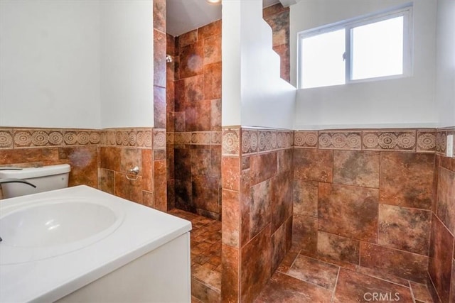 full bath with a wainscoted wall, tile walls, walk in shower, and a sink