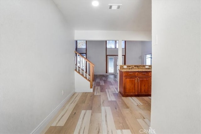 corridor featuring light wood-type flooring, baseboards, stairs, and visible vents