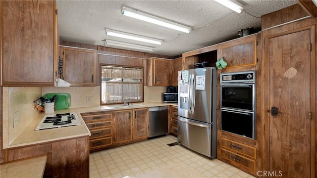 kitchen featuring a sink, light floors, stainless steel appliances, and light countertops