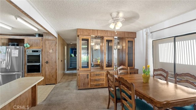 dining room with a textured ceiling, ceiling fan, and wood walls