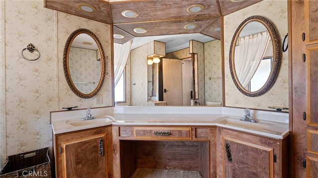 bathroom with double vanity, a sink, and wallpapered walls