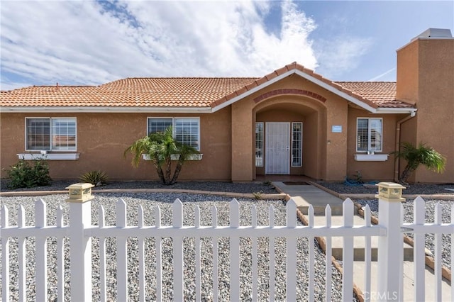 view of front facade featuring a fenced front yard, a tile roof, and stucco siding