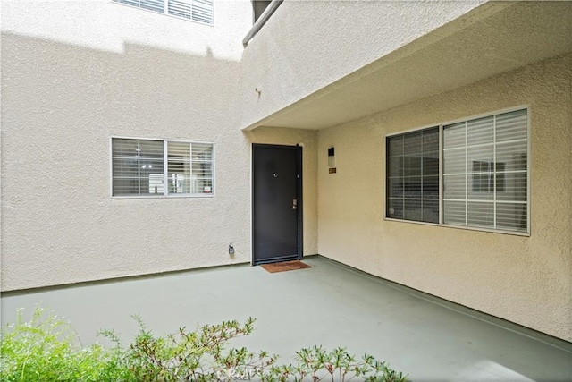 entrance to property featuring a patio area and stucco siding