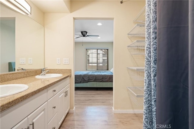 bathroom with double vanity, ensuite bath, ceiling fan, wood finished floors, and a sink