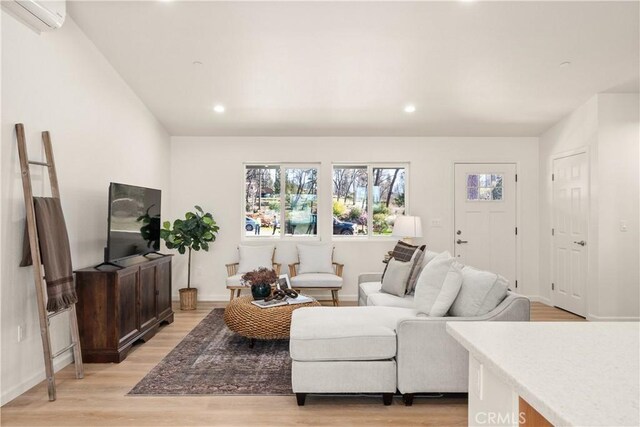 living area featuring recessed lighting, a wall mounted air conditioner, and light wood finished floors