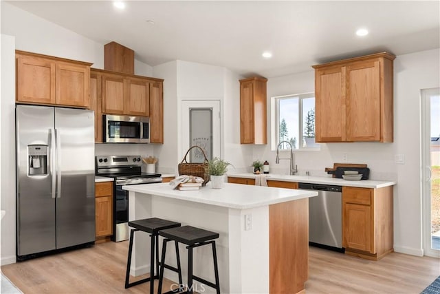 kitchen featuring appliances with stainless steel finishes, light countertops, a sink, and a kitchen island