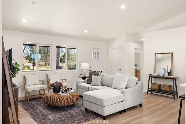 living room featuring baseboards, recessed lighting, lofted ceiling, and light wood-style floors