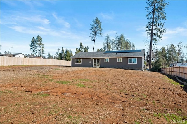 rear view of house with fence and solar panels