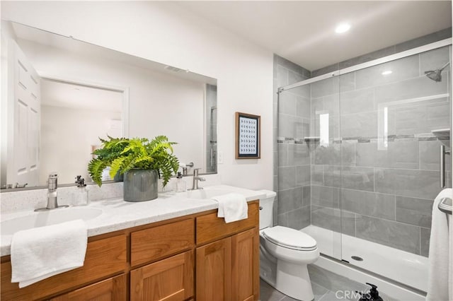 full bath featuring a stall shower, a sink, toilet, and double vanity