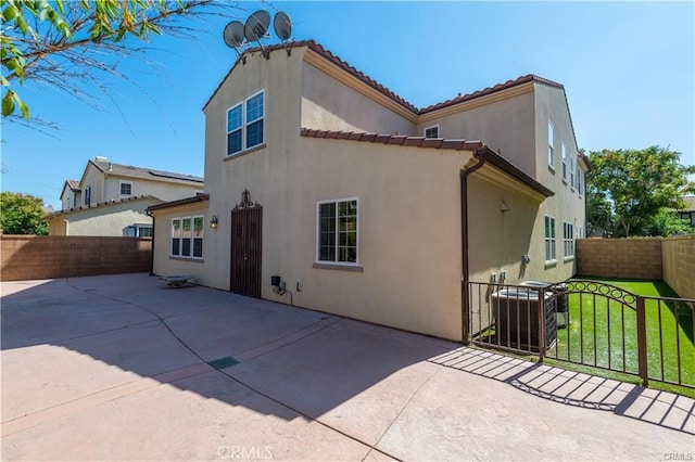 back of property featuring a patio, stucco siding, a lawn, central AC unit, and a fenced backyard