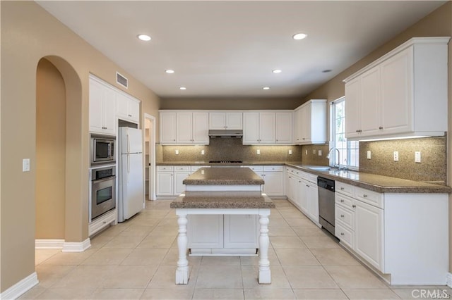 kitchen featuring visible vents, decorative backsplash, a kitchen island, stainless steel appliances, and a sink