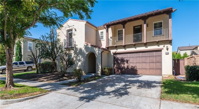 mediterranean / spanish-style home with concrete driveway, a balcony, and stucco siding