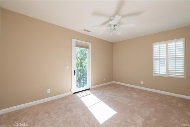 empty room featuring light colored carpet, visible vents, ceiling fan, and baseboards