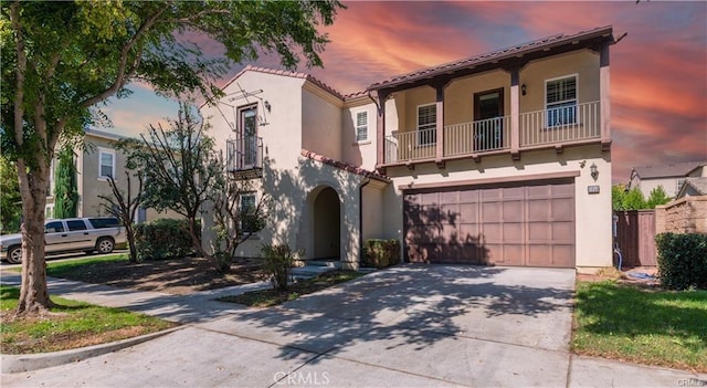 mediterranean / spanish-style home with driveway, a tile roof, a balcony, and stucco siding