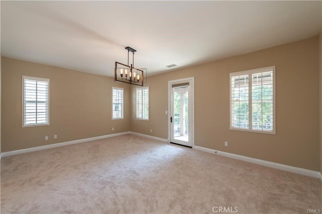 empty room featuring carpet floors, baseboards, visible vents, and a wealth of natural light