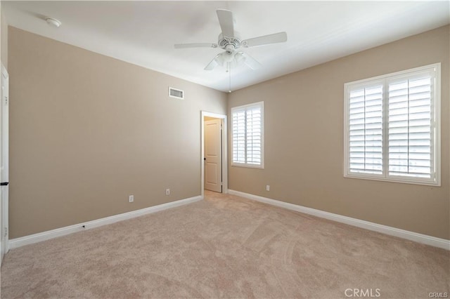 empty room featuring light carpet, baseboards, visible vents, and a healthy amount of sunlight