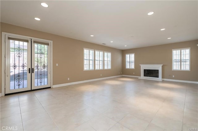 unfurnished living room with baseboards, french doors, a glass covered fireplace, and recessed lighting