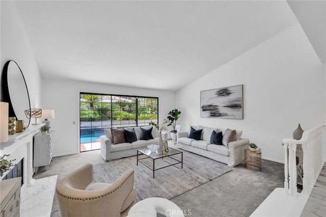 carpeted living room featuring baseboards, a premium fireplace, and vaulted ceiling