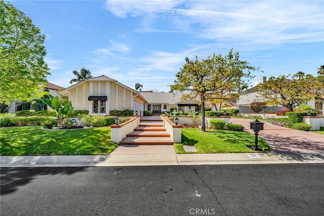 ranch-style home featuring a front lawn, a tiled roof, and stucco siding