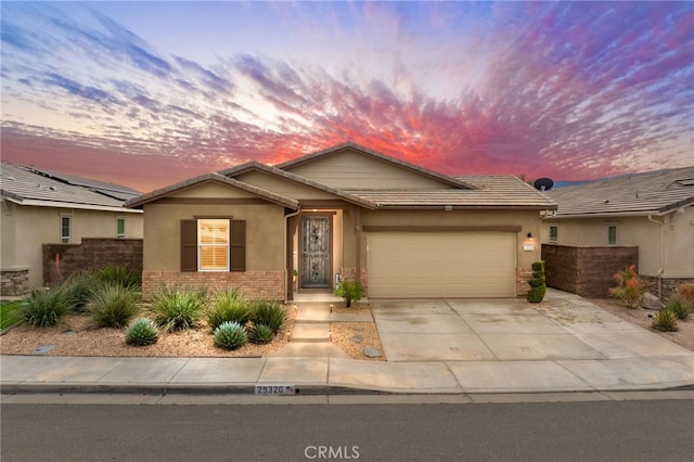 ranch-style home featuring an attached garage, brick siding, driveway, and stucco siding