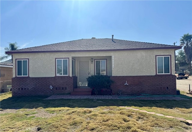 view of front of house featuring brick siding, a front lawn, and stucco siding