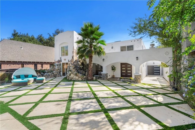 rear view of house featuring stucco siding, a patio area, and french doors