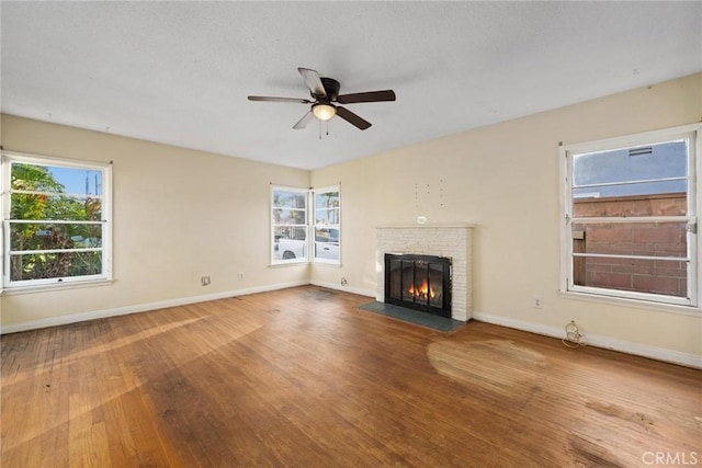 unfurnished living room featuring a fireplace, wood-type flooring, a wealth of natural light, and baseboards