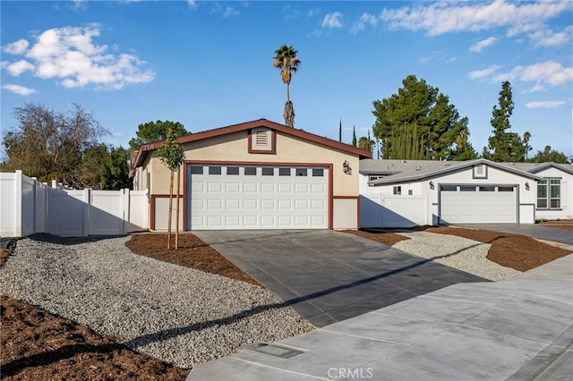 view of front of home with stucco siding, an attached garage, a gate, fence, and driveway