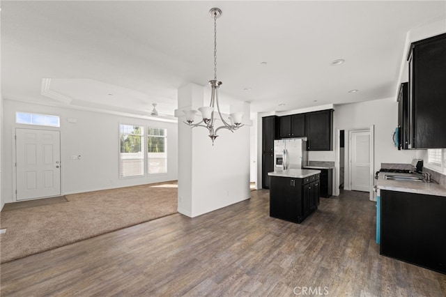 kitchen with dark cabinets, a center island, open floor plan, and stainless steel fridge