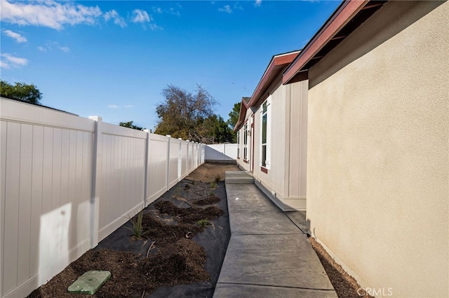 view of side of property with a fenced backyard and stucco siding