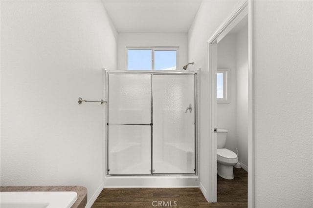 bathroom with toilet, a shower stall, baseboards, and wood finished floors