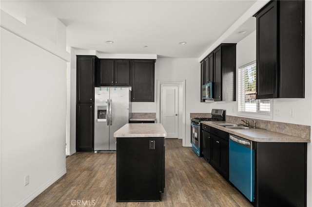 kitchen featuring dark wood-style floors, a center island, appliances with stainless steel finishes, a sink, and dark cabinetry