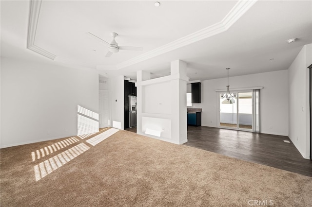 unfurnished living room with baseboards, wood finished floors, crown molding, carpet flooring, and ceiling fan with notable chandelier