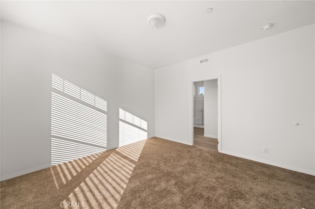 carpeted spare room with visible vents and baseboards