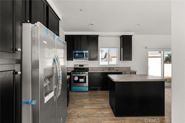 kitchen with appliances with stainless steel finishes, a sink, and dark cabinets