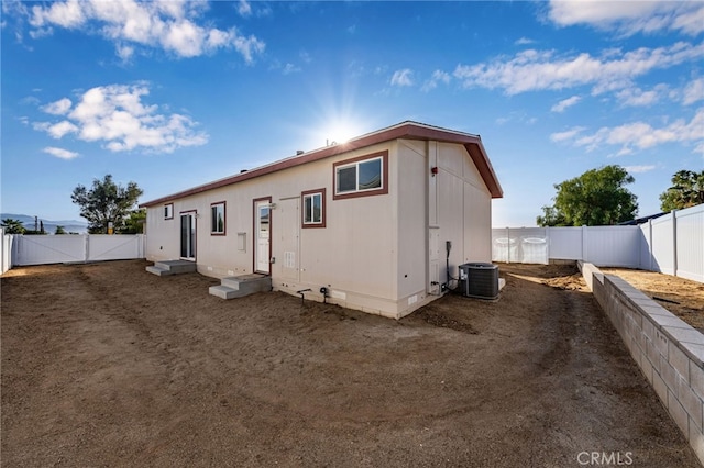 back of property featuring entry steps, crawl space, a fenced backyard, and central AC