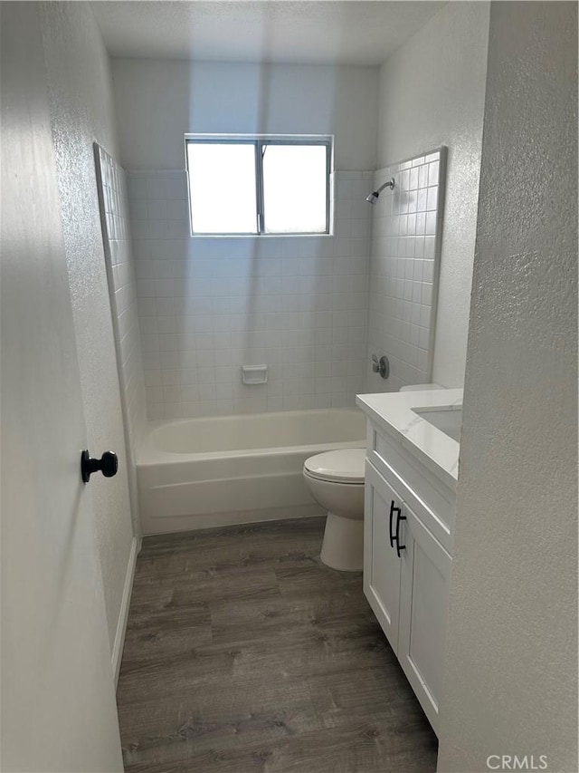 full bathroom featuring a textured wall, shower / tub combination, wood finished floors, and toilet