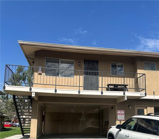 view of front facade with stairway and stucco siding