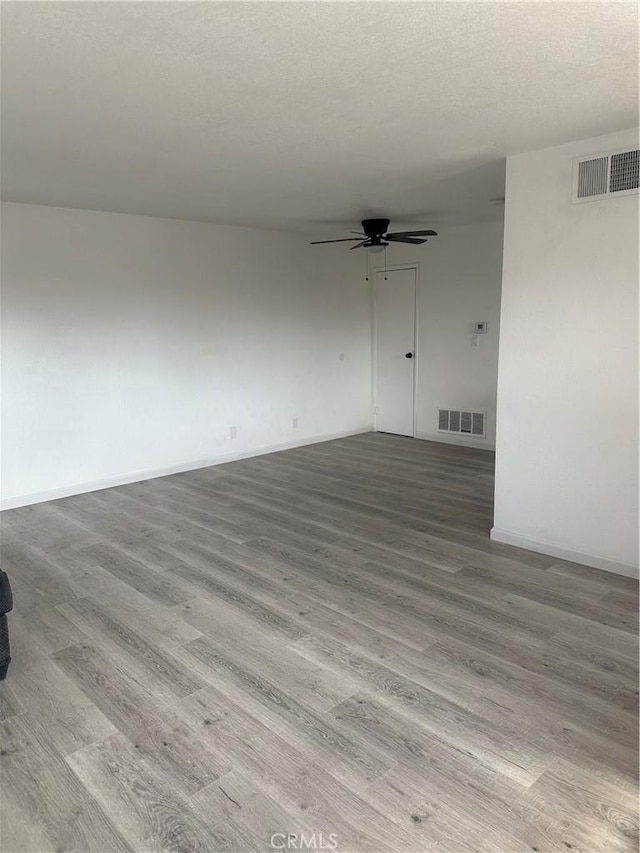 unfurnished room featuring a ceiling fan, visible vents, a textured ceiling, and wood finished floors