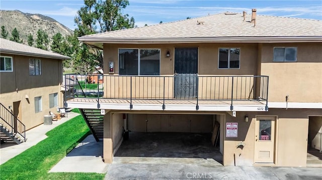 exterior space with stairway, a mountain view, and stucco siding