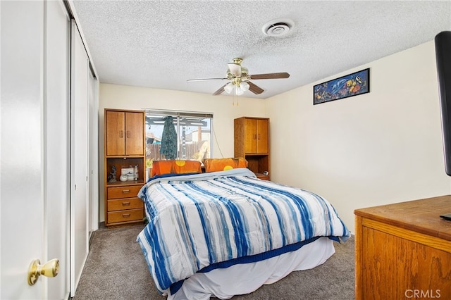 carpeted bedroom featuring a textured ceiling, visible vents, and a ceiling fan