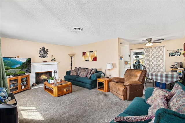 carpeted living room with a textured ceiling, visible vents, a fireplace, and a ceiling fan