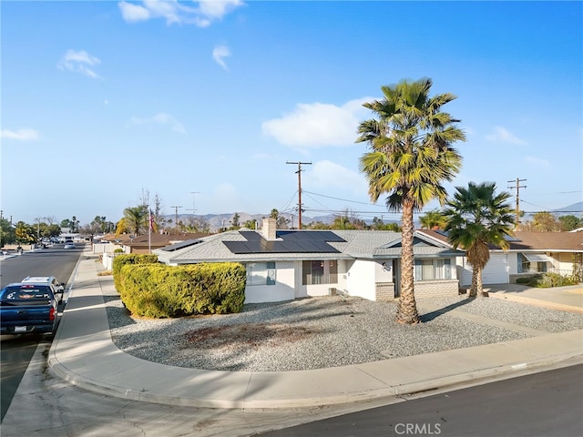 ranch-style home with a residential view and roof mounted solar panels