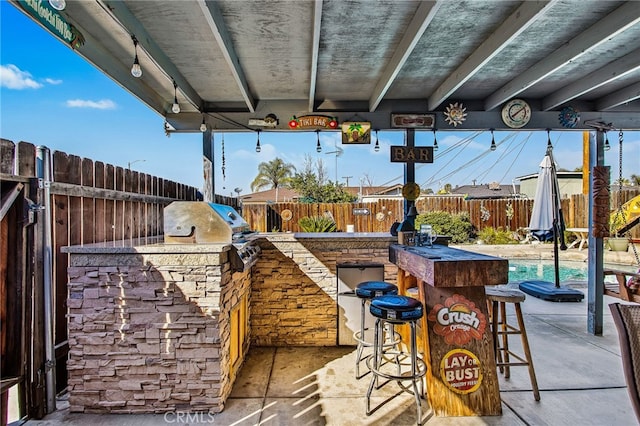 view of patio with outdoor wet bar, a fenced backyard, a grill, and area for grilling