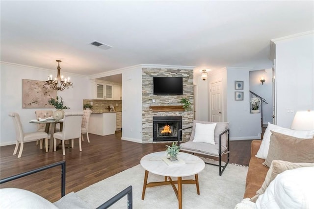 living area featuring a large fireplace, wood finished floors, visible vents, and crown molding