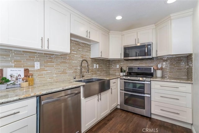 kitchen featuring tasteful backsplash, dark wood-style flooring, stainless steel appliances, white cabinetry, and a sink